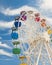 Big ferris wheel with colourful gondolas against blue sky