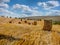 Big field hills with hay bales after harvest with cloudly blue sky