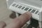 Big finger playing a miniature piano keyboard