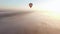 Big fliyng hot air baloon flying to the horizon over the clouds