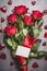 Big flowers bunch with red roses , ribbon , blank paper card and hearts on gray background