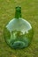 Big glass bottle of wine Empty, on green grass background.