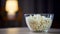 Big glass bowl of salty popcorn standing on table, treatment for home party