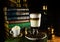Big glass with latte stand in coffee beans. Atmosphere of vinatge library with old books around and grinder on dark background.