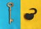 Big golden key on blue felt and open padlock on yellow felt