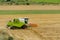 Big green combine harvester machine working in a wheat gold field, mows grass in summer field. Farm machinery harvesting grain in