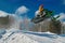 Big green Sport snowmobile jump. Cloud of snow dust from under snowmobile tracks. Concept extreme rest.