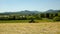 Big green tractor with haymaker working on the meadow in farmland. Haymaking in the countryside below hills