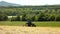 Big green tractor with haymaker working on the meadow in farmland. Haymaking in the countryside below hills