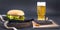 Big hamburger, beer and notebook for planning on a black background. Fast food and snacks. Free space for text. Flat lay. Copy