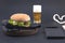 Big hamburger, beer and notebook for planning on a black background. Fast food and snacks. Free space for text. Flat lay. Copy sp