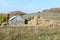 Big haystack near an old wooden shed against hills and the wood