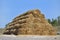 Big haystack from round bales laid in the form of a pyramid against the blue sky