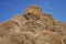 Big haystack from round bales laid in the form of a pyramid against the blue sky