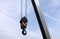Big heavy hook with yellow stripes on metal cable on construction arm crane details view