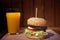 Big homemade burger with grilled meat and orange juice. Big tasty burger lunch with beef BBQ. Lunch with Glass of orange juice on