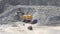 Big huge yellow excavator bucket scoops up large stones granite and pours close,