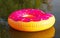 Big inflatable donut on water in sunrise time. Hipster sprinkled donut float in lake