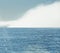 Big isolated foggy cloud on the sea. Foggy weather with detail of a sunlight reflecting in glittering sea. A rare event in the nat