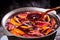 Big kettle pot of traditional hot steaming Christmas drink gluhwein mulled red spiced wine boiling with apples and citrus with