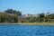 Big lake with blue water, trees and native wetland plants and villa on the cliff