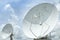 Big large white satellite dishes turn up skyward on blue sky