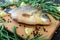 Big live carp crucian on a cutting board with rosemary branches.