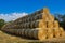 Big, long stacked round bales of straw, blue sky Czech Republic.