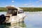 Big luxury fishing boat with cabin moored near river or lake shore in still water. Blue sky on the background. Summer adventure,