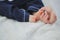 big manÐ¢s hand touches the little fingers of a child, close-up, the baby is sitting with bare feet, photo on a white background