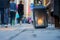 Big metal dirty lantern with burning candle inside, outdoor on a ground with blurred crowded street on a background.