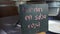 Big metal pot and black sign with pink Spanish text on a table