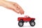 Big metal red toy car offroad with monster wheels in hand isolated on white background