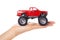 Big metal red toy car offroad with monster wheels in hand isolated on white background