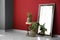 Big mirror, stand and houseplants near color wall