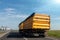 Big modern yellow grain hopper cargo truck driving on highway to silo granary storage unloading aginst clear blue sky on