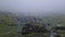 Big mountain rocks and boulders seen through the dense mist. Moody hiking scene with rainy weather