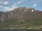 Big mountains with snowy peaks and the Flam village in Norway against the blue sunny sky