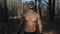 Big muscular male athlete in the forest shows muscles topless and running. Slow motion