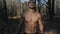 Big muscular male athlete in the forest shows muscles topless and running. Slow motion