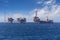 Big offshore oil rig drilling platform complex with anchored ship