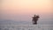 Big oil rig in the sea, colorful sky in the evening silhouettes of the mountains