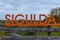 Big orange inscription Sigulda on wooden balustrade of viewpoint in Sigulda Medieval Castle territory