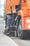 Big orange machine clears the asphalt with a sweeper