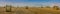 big panoram of harvested wheat field, bales of straw in rolls, against the background of a beautiful sky