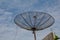 Big parabolic antenna on the roof against blue cloudy sky