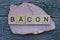 Big piece of bacon meat with the word from wooden letters