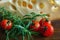 Big piece of cheese with holes lying with fresh twigs rosemary and cherry tomatoes on a wooden cutting board background.