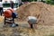 A big pile of sand and a cement mixer and a cement cart for starting work