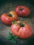 Big pink tomato and basil on a wooden background
